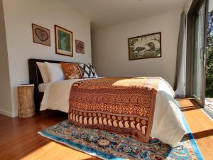 a bedroom with a bed with a rug on the floor at Kia Noho in Havelock North