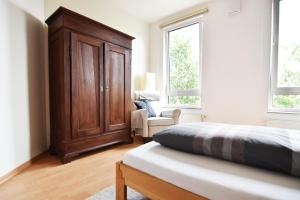 a bedroom with a bed and a wooden cabinet at Work and Stay Apartment Cologne- Fühlinger See 