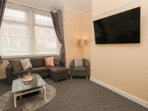 ein Wohnzimmer mit einem Sofa und einem TV in der Unterkunft St Heliers in Blackpool