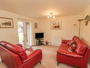 a living room with two red leather couches and a television at White Goose Cottage in Whitby