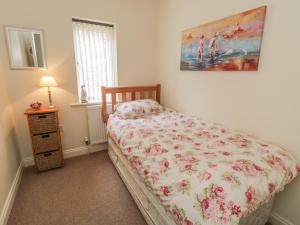 a bedroom with a bed with a floral comforter and a window at White Goose Cottage in Whitby