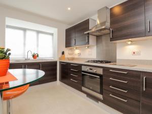 a kitchen with wooden cabinets and a glass table at 60 Galley Hill View in Bexhill