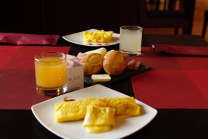 two plates of breakfast food on a table with orange juice at Hotel Nuvò in Naples