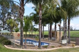 a pool with palm trees in front of a building at Tokemata Retreat in Cobram