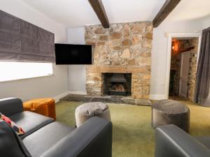 a living room with a stone fireplace and a tv at Culdrose Manor in Helston