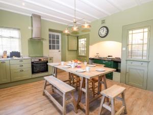 Culdrose Manor في هيلستون: مطبخ كبير مع طاولة وكراسي خشبية