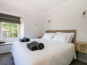 1 dormitorio con 1 cama blanca grande y toallas. en Culdrose Manor en Helston