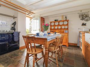 a kitchen with a wooden table and chairs at Higher Roskorwell Cottage in Helston