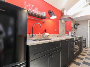 cocina con fregadero y pared roja en Morawel Fach, en Newport