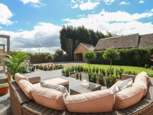 a patio with a couch and a glass table at Upper Barn in Stafford