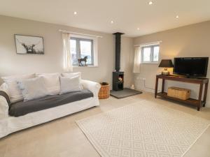 Upper Barn في ستافورد: غرفة معيشة مع أريكة بيضاء وتلفزيون بشاشة مسطحة