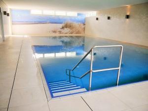 a swimming pool with blue water and stairs in a room at Seedeich Apartment in Cuxhaven