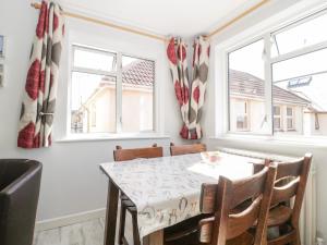 a dining room with a table and chairs and windows at Swanage Town Apartment in Swanage