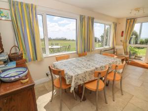 Un comedor con mesa y sillas y ventanas. en Rospletha Bungalow, en Penzance 20 fotos más
