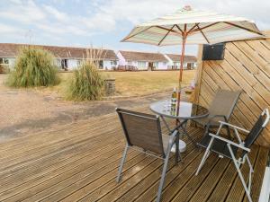 a table and chairs with an umbrella on a deck at Buddleia Cottage in Seaview