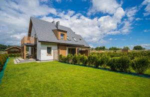 une maison avec une pelouse verte devant elle dans l'établissement Villa Arkadia RESORT, à Łukęcin