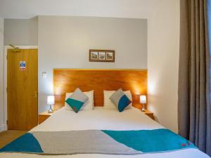 a bedroom with a large bed with blue pillows at OYO Eastbank Hotel, Speyside Scotland in Rothes