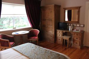 a bedroom with a bed and a desk and a television at Adare Country House in Adare