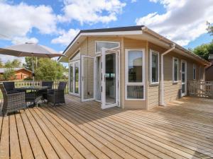 a house with a wooden deck with a patio at Pentney Lodge in Kings Lynn