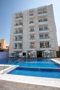 a hotel with a swimming pool in front of a building at Best Western Plus Larco Hotel in Larnaka