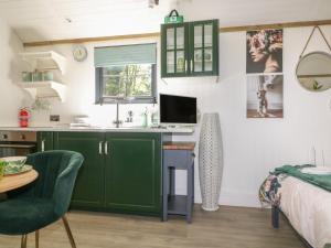 a kitchen with green cabinets and a desk in a room at High Rigg Shepherd's Hideaway in Brampton +5 photos