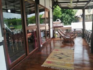 eine Veranda mit Glastüren sowie einem Tisch und Stühlen in der Unterkunft Chateau Orientale Resort in Luang Prabang