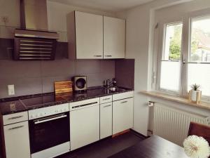 uma cozinha com armários brancos e um forno com placa de fogão em Ferienwohnung Südschwarzwald em Wehr