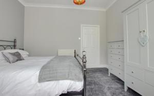 a white bedroom with a bed and a dresser at Central Park Place in Whitby