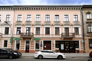 a white car parked in front of a pink building at Native Apartments Czysta 5 in Kraków