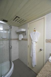 e bagno con doccia e accappatoio appeso a una porta. di Hotel Muscat Holiday a Mascate