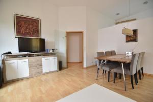 a dining room with a table and a television at Work and Stay Apartment Cologne- Fühlinger See in Chorweiler +12 photos