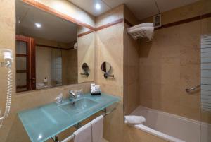 a bathroom with a sink and a tub and a mirror at Hotel MS Maestranza Málaga in Málaga
