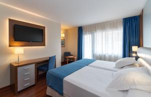 a hotel room with a bed and a desk with a television at Hotel MS Maestranza Málaga in Málaga