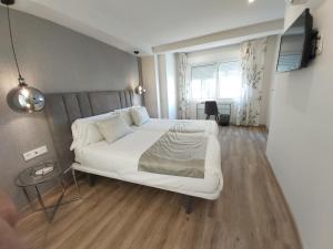 sypialnia z dużym białym łóżkiem i stołem w obiekcie Del Parque Flats Flores Premium w Maladze