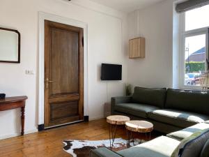 sala de estar con sofá verde y puerta en Authentic Stays - 6p-apartment, en Eijsden