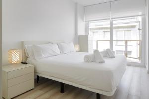 a white bedroom with a large bed with towels on it at Apartamento Isaga Lecera in Zarautz