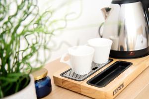 two white coffee cups sitting on a cutting board at Résidence La Canopée in Strasbourg