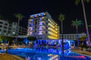 a hotel with a pool and palm trees at night at Anonymous Beach Hotel (Adults 16+) in Ayia Napa