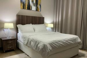 1 dormitorio con 1 cama con sábanas blancas y 2 lámparas en Grany Apartment - Palm Village, en Dar es Salaam