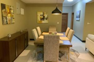 uma sala de jantar com uma mesa de madeira e cadeiras em Grany Apartment - Palm Village em Dar es Salaam