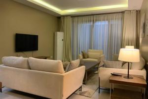 sala de estar con sofá blanco y TV en Grany Apartment - Palm Village, en Dar es Salaam