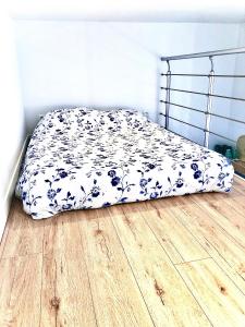 a bed with a blue and white blanket on a wooden floor at Le Petit Coeur in Le Havre