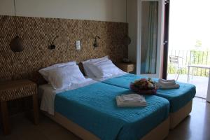 een slaapkamer met een blauw bed, handdoeken en een raam bij Dassia Beach Hotel in Dassia