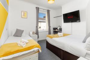 een slaapkamer met 2 bedden en een flatscreen-tv bij Cosy Anfield Guesthouse - FREE parking in Liverpool