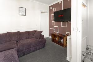 een woonkamer met een bank en een flatscreen-tv bij Cosy Anfield Guesthouse - FREE parking in Liverpool