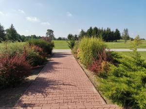 un camino de ladrillo en un parque con arbustos en Golf Hotel Lisia Polana en Pomocnia
