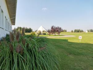 un campo de hierba con una tienda blanca en el fondo en Golf Hotel Lisia Polana en Pomocnia