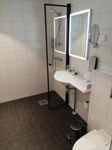 a bathroom with a sink, mirror, and toilet at Pilot Airport Hotel in Vantaa