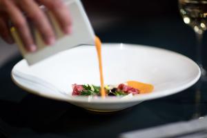 a person is pouring sauce onto a plate of food at Sir Anthony in Playa de las Americas