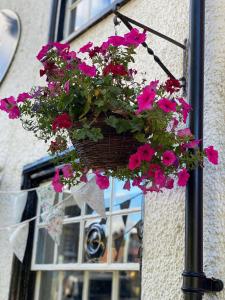a basket of flowers hanging from the side of a building at Fleur De Lys Bed & Breakfast in Dorchester on Thames
